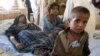 An injured Pakistani woman is surrounded by her children at a makeshift hospital in the earthquake-devastated Awaran district of Balochistan Province. 