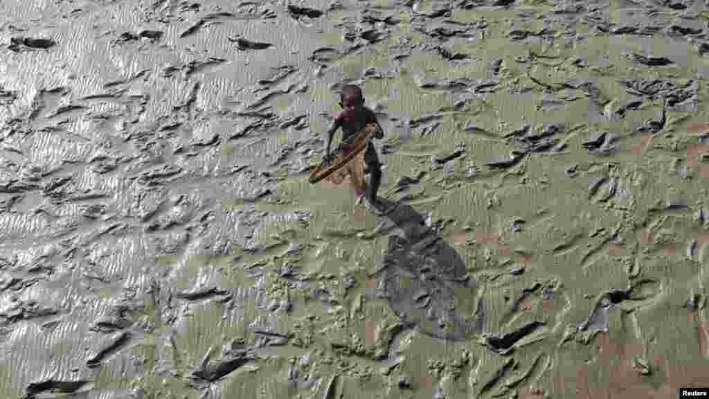 A boy runs to receive alms from pilgrims near the banks of the Ganges River south of Kolkata, India. (Photo by Rupak De Chowdhuri for Reuters)