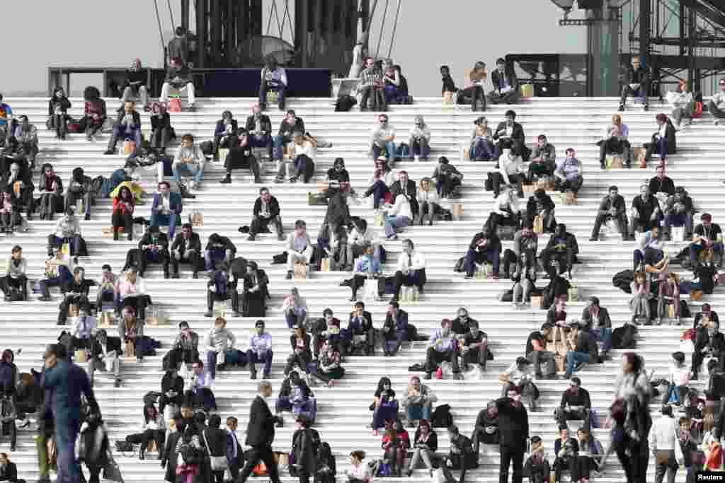 Businessmen enjoy the good weather at lunch time on the steps of the Arche de la Defense, in the financial and business district west of Paris, as warm and sunny weather continues in France. (Reuters/Charles Platiau)