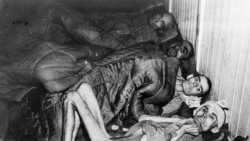 Четверо виснажених в’язнів концтабору «Аушвіц» після звільнення