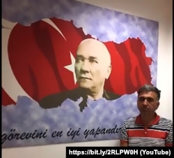 Стоп-кадр: Саліх Зекі Їгіт після депортації до Туреччини. На цьому кадрі не видно, що руки в нього зв’язані. Біля цього ж самого прапора покажуть і Юсуфа Інана