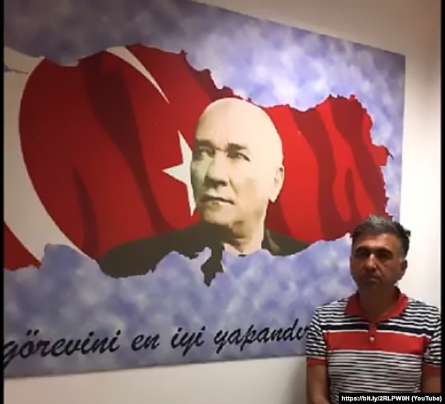 Стоп-кадр: Саліх Зекі Їгіт після депортації до Туреччини. На цьому кадрі не видно, що руки в нього зв’язані. Біля цього ж самого прапора покажуть і Юсуфа Інана