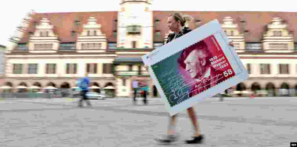 A young woman carries an oversized Wagner stamp in Leipzig, Germany. The German Finance Ministry issued a commemorative 10-euro coin and a postage stamp to mark the composer&#39;s bicentennial.