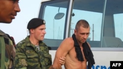 A Russian serviceman escorts one of the eight suspected hijackers of the "Arctic Sea" cargo ship in Cape Verde.