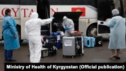 Люди в защитных костюмах проводят досмотр багажа прибывших в Кыргызстан. Архивное фото.