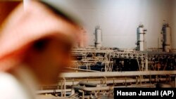 A Saudi official stands in front of a giant Saudi oil industry picture at a hotel in the Red Sea port city of Jiddah, Saudi Arabia, on Saturday, June 21, 2008, ahead of a major oil summit.