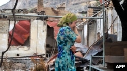 An ethnic Uzbek woman cries as she passes by a burnt-out house in Osh on June 24, 2010.