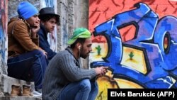 Migrants sit in front of an abandoned building in the main park of the northwestern Bosnian town of Velika Kladusa earlier this summer. 