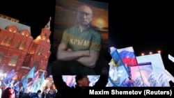 Участник митинга-концерта к четвертой годовщине аннексии Крыма держит плакат с изображением президента России Владимира Путина. Москва, 18 марта 2018 года.