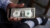 An Iranian street money changer holds a U.S. banknote in downtown Tehran, July 30, 2018