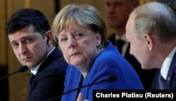 Ukrainian President Volodymyr Zelenskiy (left) and German Chancellor Angela Merkel (center) listen to Putin at a joint news conference after talks in Paris in December 2019.