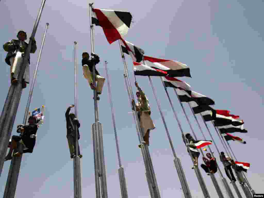 Supporters of Yemen's President Ali Abdullah Saleh climb flag poles during a rally in Sanaa on May 13.Photo by Khaled Abdullah for Reuters