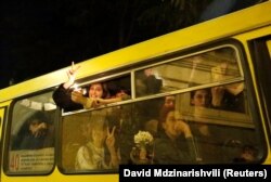 A protester gestures as she and others are bussed away from the site of the protest in the early hours of May 14.