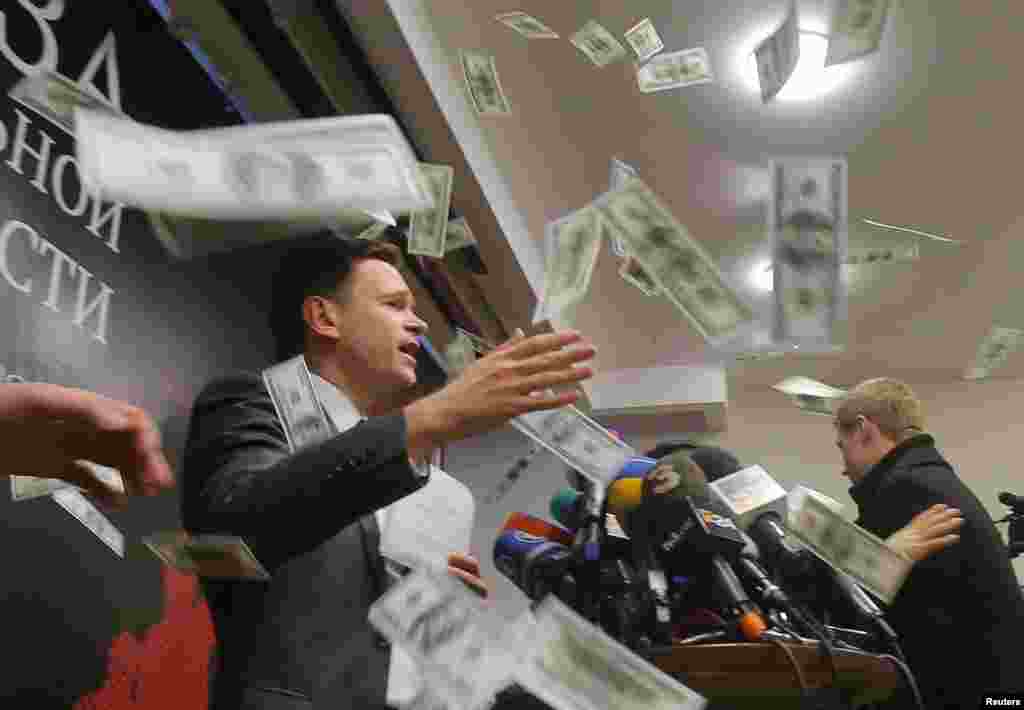 An unidentified person throws pieces of paper, resembling banknotes, as Russian opposition figure Ilya Yashin (left) presents his report, titled National Security Threat and dedicated to the current situation in Chechnya and its leader, Ramzan Kadyrov, on February 23. (Reuters/Maksim Shemetov)