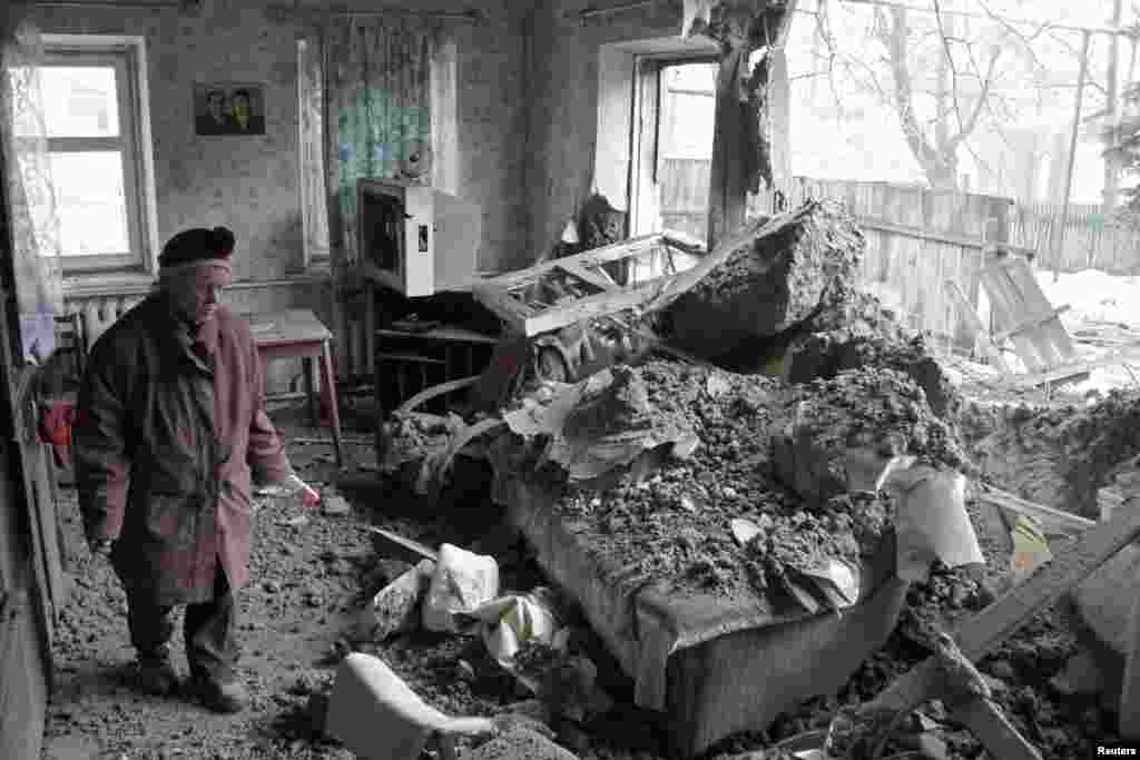 A woman surveys damage to a house in the suburbs of Donetsk that locals said was damaged by shelling.