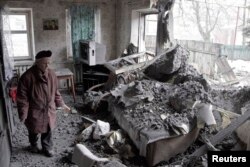 O femeie privește o locuință distrusă de bombardamente în Donețk, 30 ian, 2015