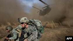 FILE U.S. and Afghan soldiers race to get out of the way of a CH-47 Chinook helicopter landing.