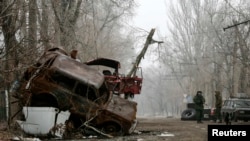 Pro-Russian separatists stand guard next to cars damaged during fighting between the rebels and Ukrainian government forces near Donetsk's airport on December 16.