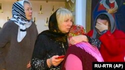 A group of women comfort each other after a memorial service in the Russian Orthodox Church in Kizlyar for the victims of a mass shooting in the city in February 18.