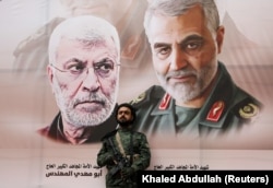 A Huthi militant stands by a poster of Iraqi militia commander Abu Mahdi al-Muhandis and Iranian military commander Qassem Soleimani during a rally by Huthi supporters to denounce the U.S. killing of both commanders, in Sanaa, Yemen, in 2020.