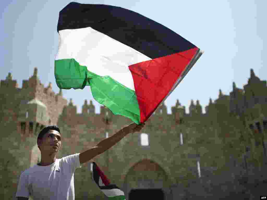 A Palestinian man at Jerusalem's Damascus Gate waves his national flag during a protest on September 21 ahead of his country's bid for statehood recognition at the United Nations in New York. (Photo taken by Marco Longari for AFP)