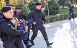 Полицейлер оппозициялық қозғалыс жетекшісі митинг орны ретінде белгілеген жерден ер адамды ұстап барады. Алматы, 26 қазан 2019 жыл.