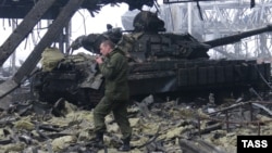 یکی از شبه‌نظامیان از کنار یک تانک سوخته ارتش اوکراین در فرودگاه دونتسک می‌گذرد