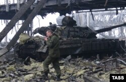 A pro-Russian militants walks past a tank at the Donetsk airport.