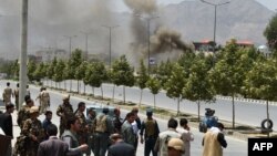 Аўганскія органы бясьпекі і мінакі глядзець, як чорны дым хвалямі ідзе ад будынку аўганскага парлямэнту ў Кабуле, 22 чэрвеня 2015 году