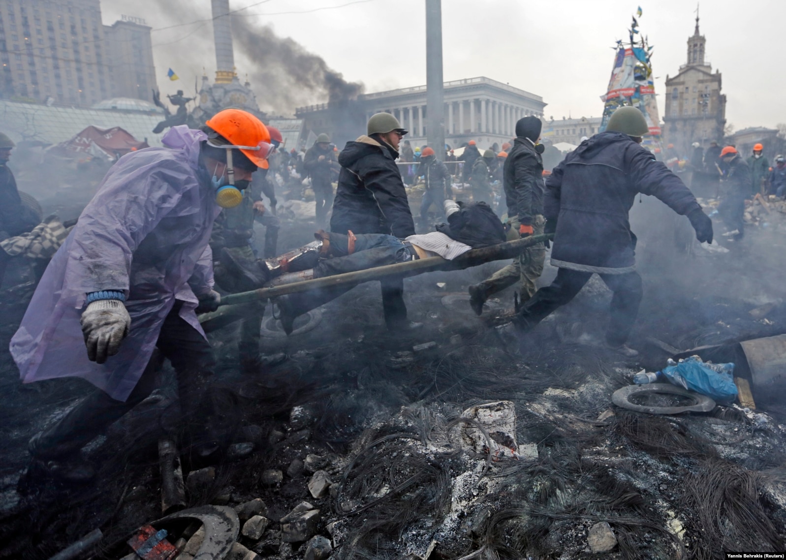 Antigovernment protesters carry an injured man on a stretcher after clashes with riot police on Independence Square in Kyiv on February 20, 2014.