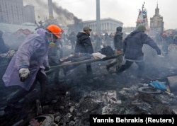 Antigovernment protesters carry an injured man on a stretcher after clashes with riot police on Independence Square in Kyiv on February 20, 2014.