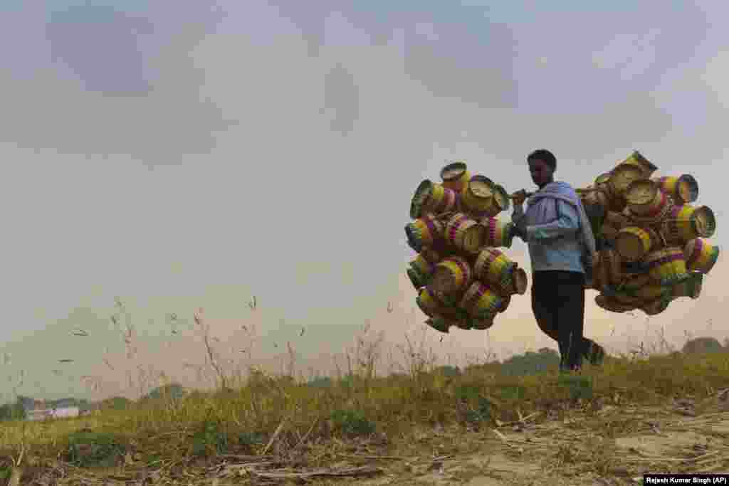 An Indian villager named Dharampal, 37, carries cane baskets for sale on the outskirts of Allahabad. The baskets are sold for 35 rupees (50 U.S. cents) apiece. Dharampal says he earns between 8,000 to 10,000 rupees ($125 to $150) a month. (AP/Rajesh Kumar Singh)