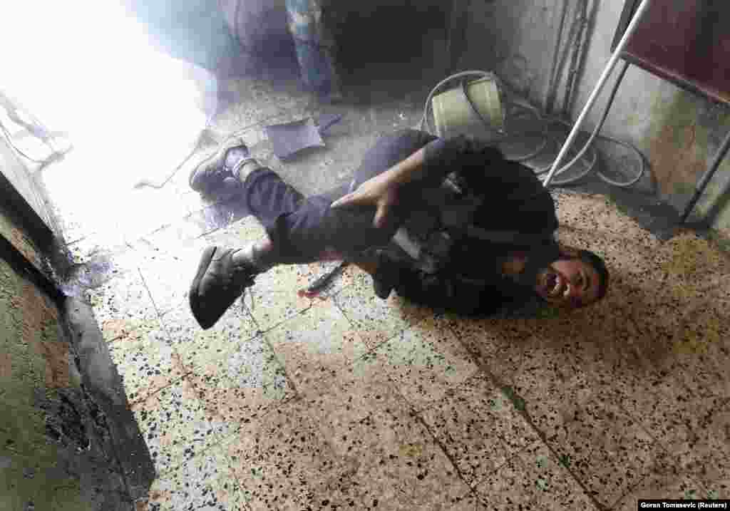 A Syrian rebel fighter screams after being wounded by shrapnel from an explosion in August 2012. Moments before, the rebel had been using his knife (seen on the floor) to serve lunch with a group of fellow fighters.