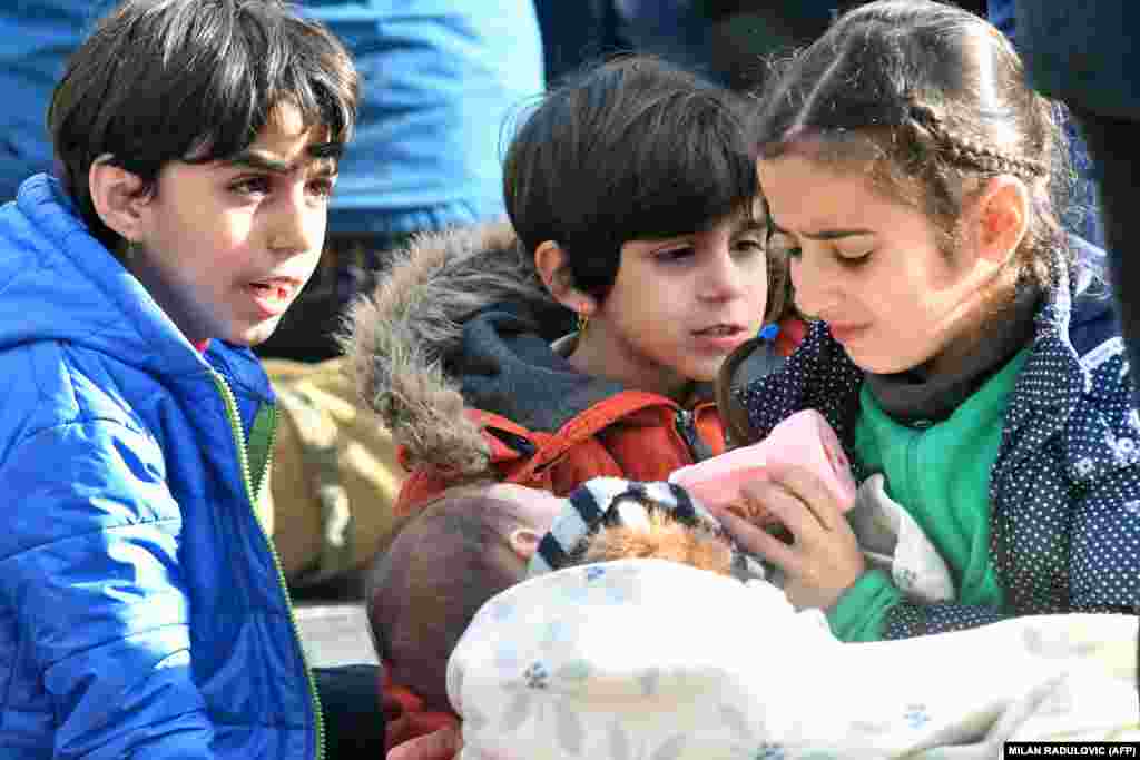 Migrant children feed an infant at the Maljevac border crossing near the northern Bosnian town of Velika Kladusa. Illegal migrants gather near the border crossing in an attempt to cross into neighboring Croatia. (AFP/Milan Radulovic)