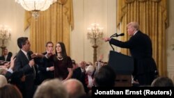 Сотрудница Белого дома пытается отобрать микрофон у репортера CNN Джима Акосты во время пресс-конференции Трампа после промежуточных выборов в конгресс. Вашингтон, 7 ноября 2018 года.