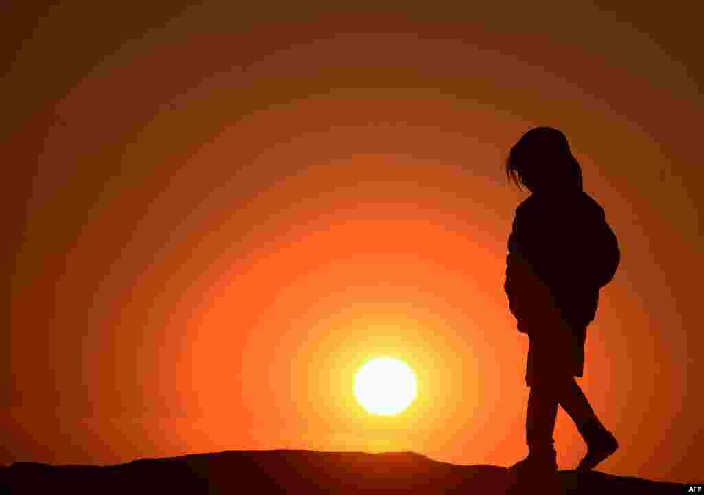 An Afghan girl walks outside her home during sunset on the outskirts of Herat. (AFP/Aref Karimi)