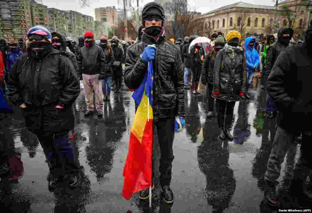 A man holds European and Romanian flags during a protest outside government headquarters in Bucharest against planned changes to the Romania's legal system. (AFP/Daniel Mihailescu)