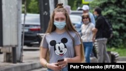 Девушка в защитной маске идет по улице. Алматы, 9 мая 2020 года.
