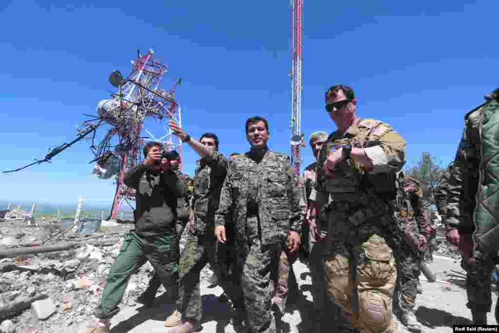 A U.S. military commander (right) with YPG fighters as they inspect the damage done to a YPG base after it was hit by Turkish air strikes.&nbsp;