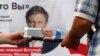 Сторонник "Единой России" раздает газеты с портретом президента Путина у предвыборного плаката партии "Яблоко" 
