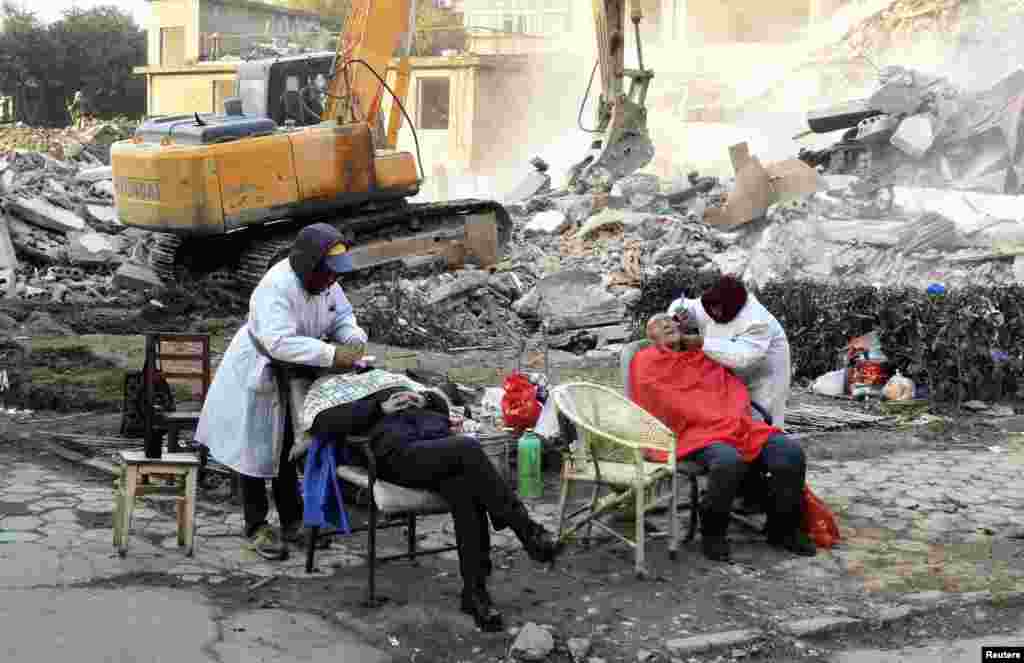 Men get shaves next to an excavator working at a demolition site in the Chinese city of Nanchang in Jiangxi Province. (Reuters)