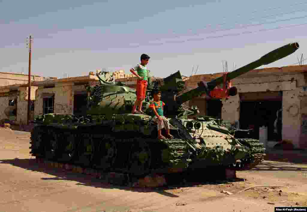 Boys play on a damaged military tank that belonged to forces loyal to Syrian President Bashar al-Assad in the rebel-held southern town of Bosra al-Sham, is Syria&#39;s Deraa Governorate, on September 19. (Reuters/Alaa al-Faqir)