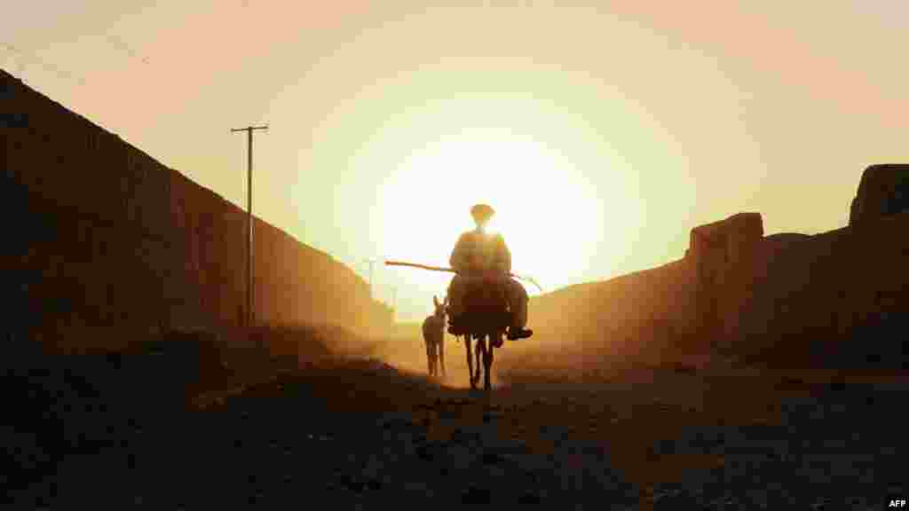 An Afghan villager rides a donkey in a dusty road in the Zadyan district of Balkh Province on September 23. (AFP/Qais Usyan)