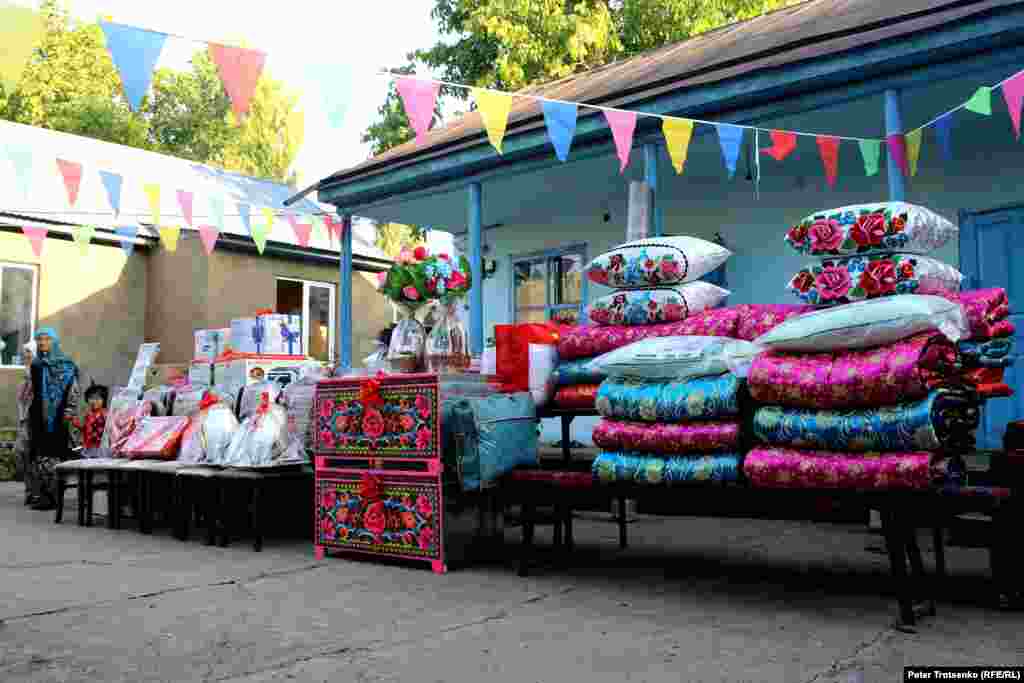 The dowry stands in the courtyard, each piece decorated with flowers and ribbons. It usually includes utensils, pillows, and blankets, but also modern items such as a refrigerator or washing machine.
