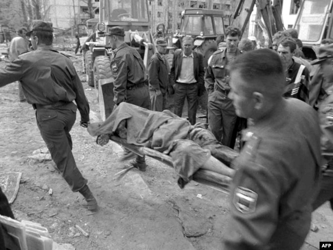 Ekipet e shpëtimit shihen duke bartur trupin e një viktime pasi sulmi me makinë-bombë ka rezultuar me shkatërrim të një ndërtese në Volgodonsk. Fotografi e vitit 1999.