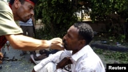 A rebel fighter slaps a wounded man accused of being a mercenary fighting for Muammar Qaddafi outside a fire station in Tripoli 