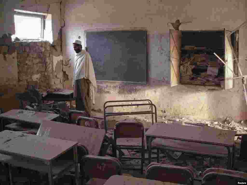 A man walks through a destroyed classroom of a boys' school hit by a bomb in Landikotal in northwest Pakistan. Unidentified men planted the bomb, which resulted in no casualties. (REUTERS/Shahid Shinwari)