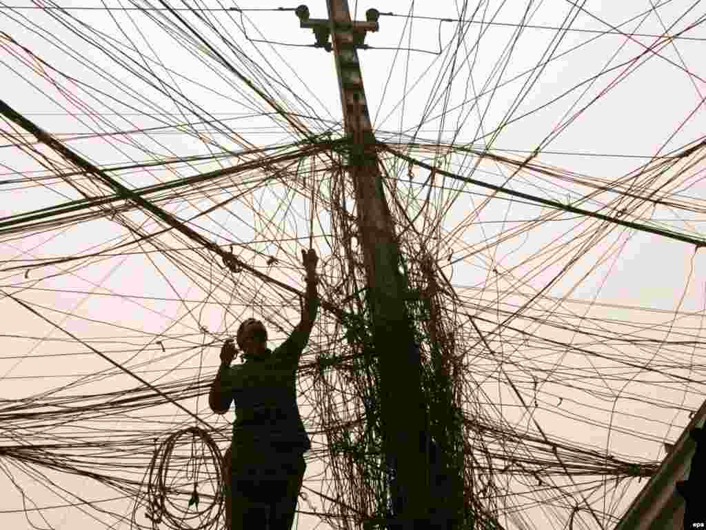 An Iraqi electrician checks a tangle of wires, all of which lead to a generator that runs when the national power grid is down, in Baghdad's Karrada district, on June 23. A wave of protests swept across Iraq against frequent power cuts, which led to the resignation of the minister of electricity. (Photo by Ali Abbas/epa)