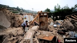 China -- A woman is seen on ruins of a damaged house after a 6.6 magnitude earthquake hit Minxian county, Dingxi, Gansu province, July 23, 2013
