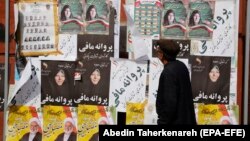An Iranian man looks at electoral posters and fliers during the last day of election campaign, in Tehran, February 19, 2020